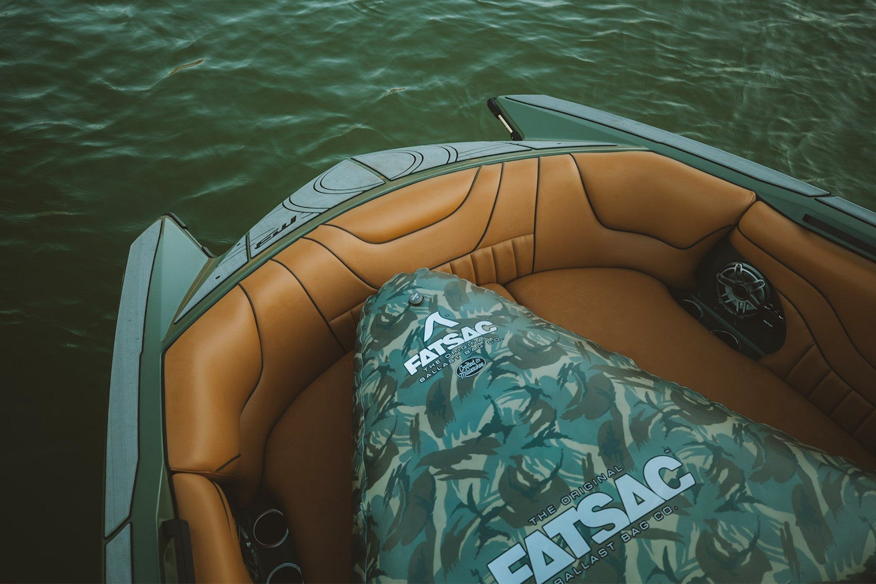 FATSAC ballast bag with a green camouflage design resting in the bow seating of a luxury boat.