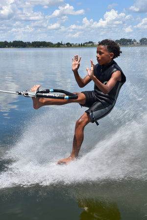 Boy barefoot skiing with a foot in the Front Toe Handle Full Wrap, hands raised.