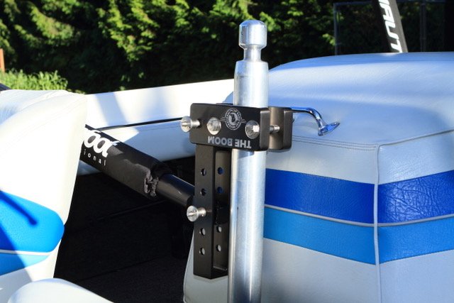 Boom Height Adjuster mounting a boom to the side of a blue and white boat.