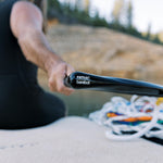 Close-up of a person holding a black handle with logo, multicolored rope coiled in the background.